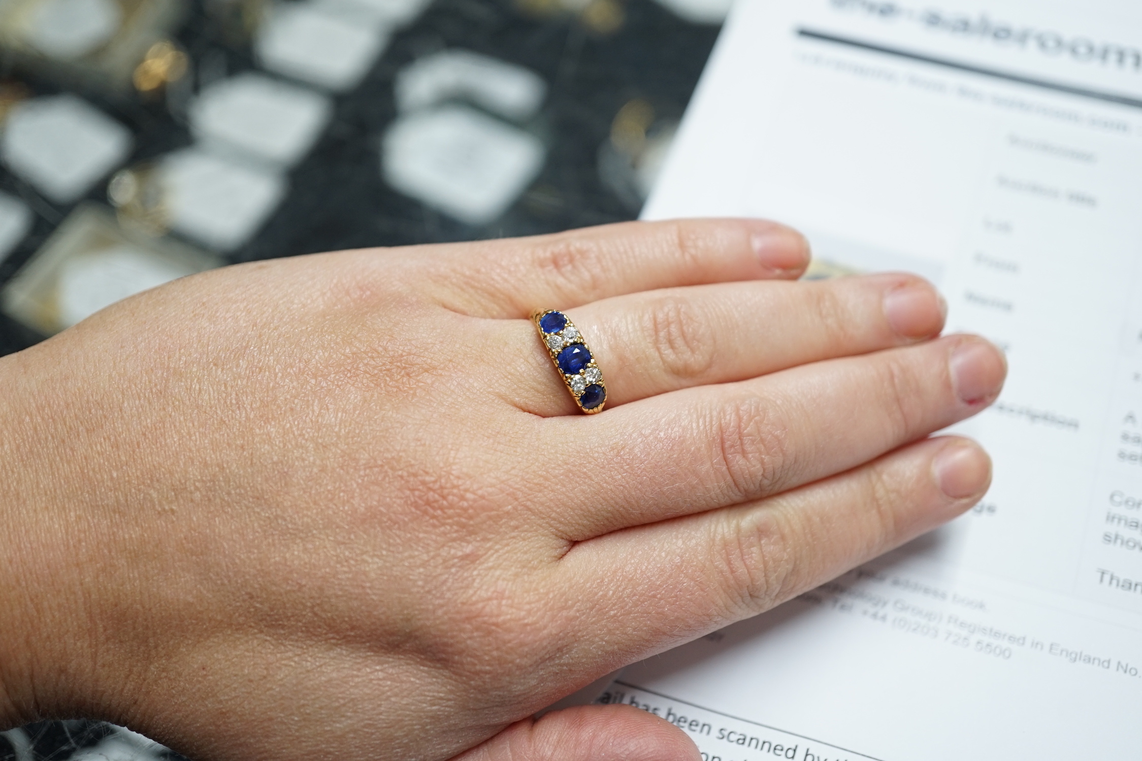 A late Victorian 18ct gold and three stone sapphire set ring, with four stone diamond set spacers, size M, gross weight 4.1 grams.